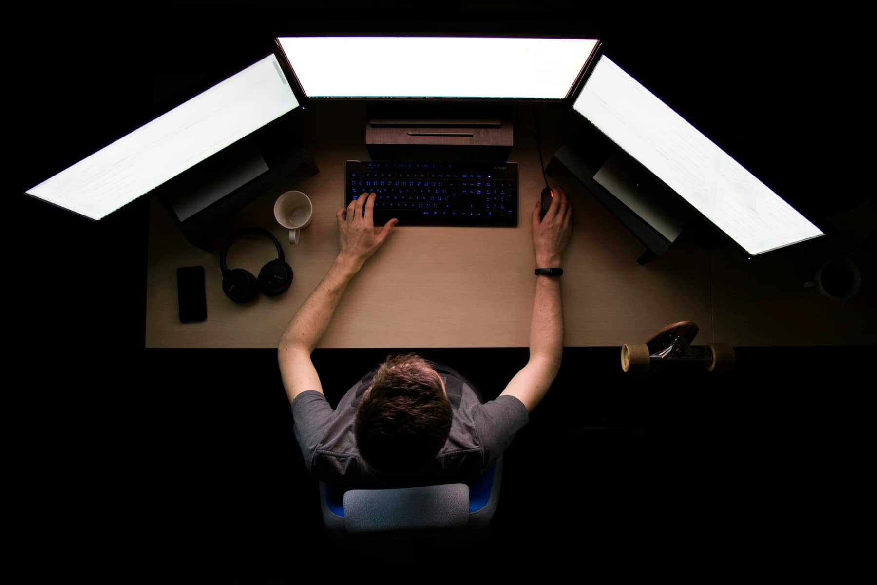 Engineer working at a triple-monitor workstation in a dark studio